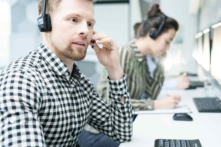呼叫中心男性座席使用VoIP蓝牙耳机。