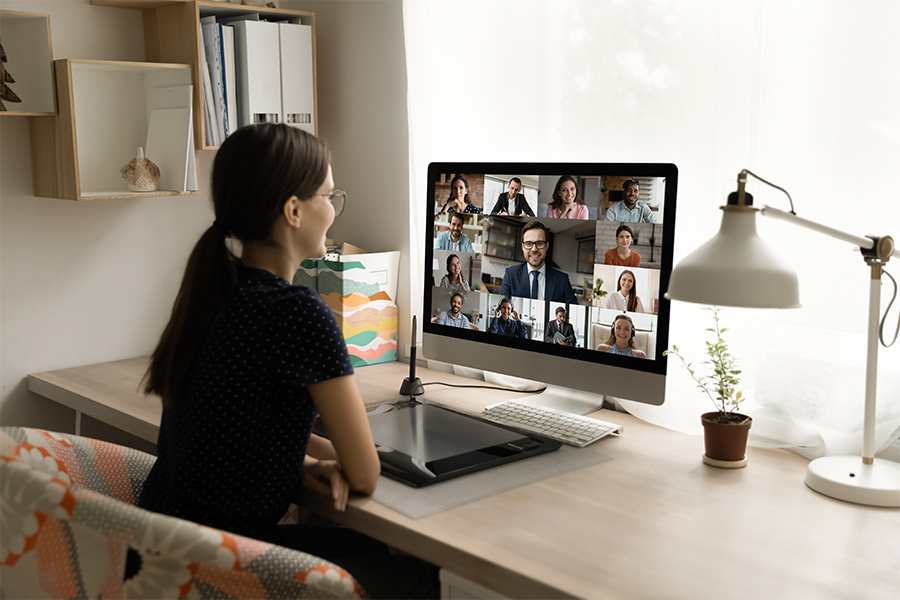 后后视图快乐的千禧女员工看着电脑显示器，举行在线视频通话谈判会议。