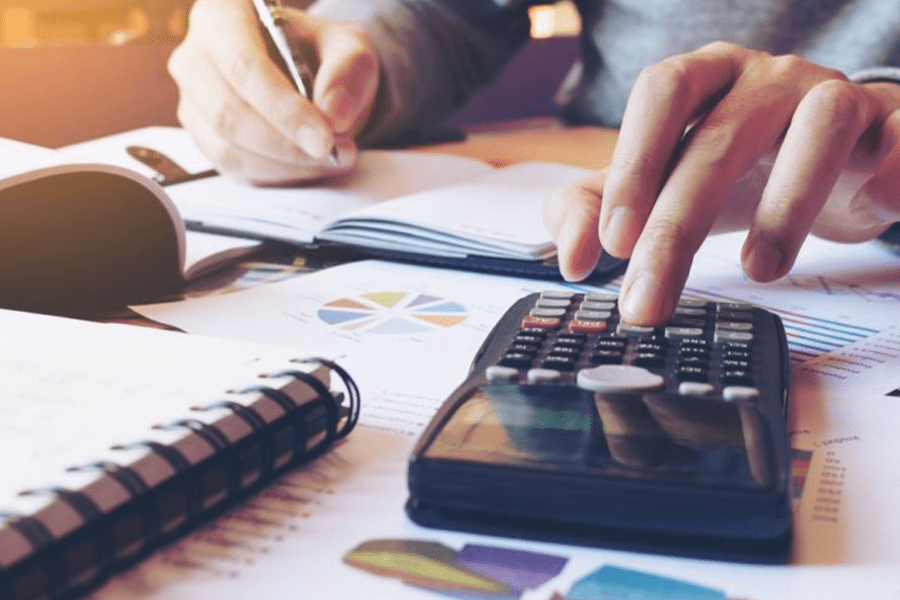 Man writing and entering numbers on calculator.