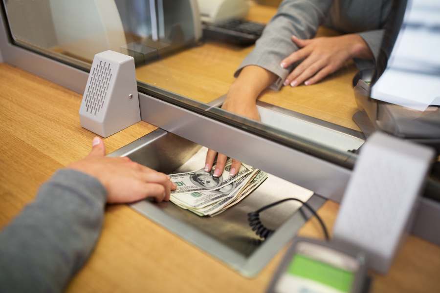 Clerk giving cash money to customer at bank office or currency exchanger.