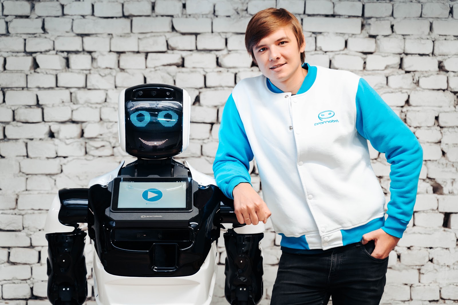 young man standing next to a robot