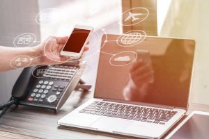 Hand holding phone, laptop and telephone