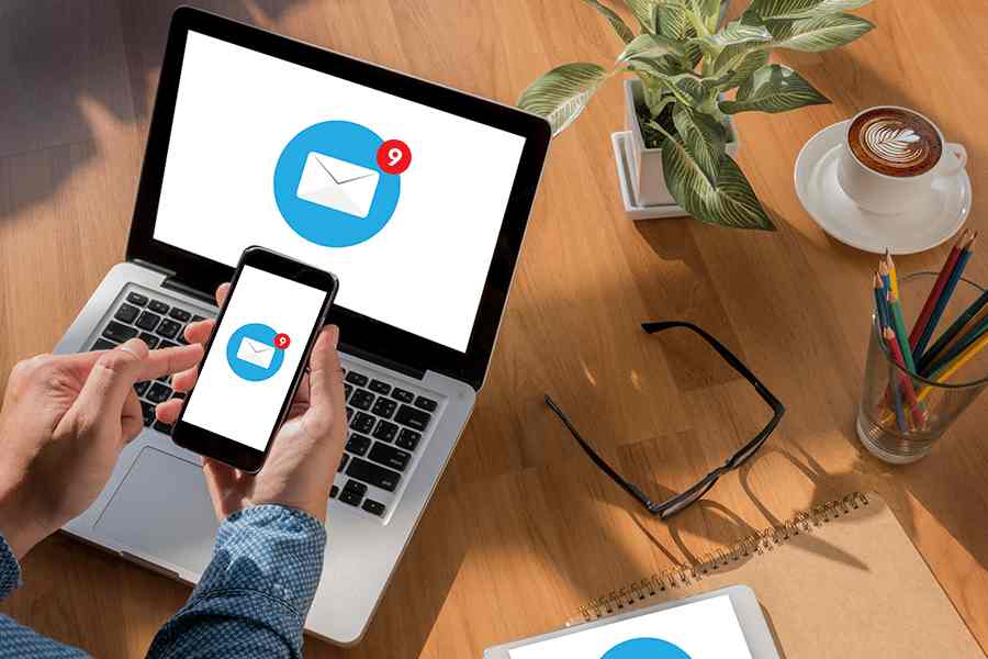 Phone and laptop with email notification icon on screen.