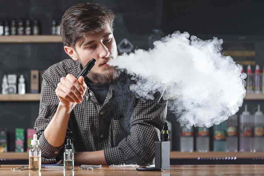 A young man vaping e-cigarette.