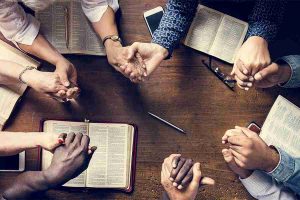 people holding hands and bible