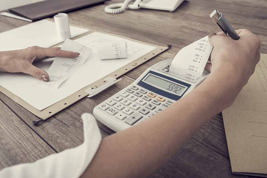 Woman using calculator calculating expenses.