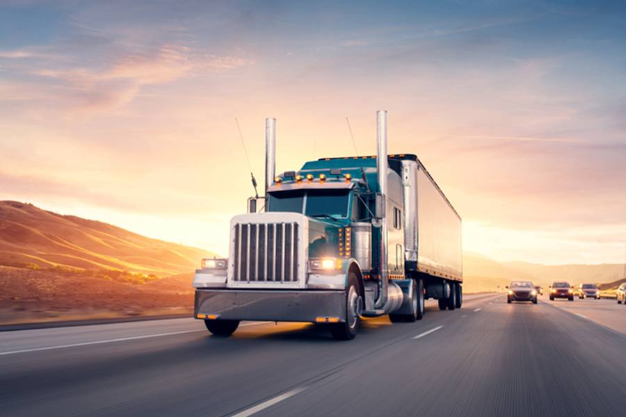 American style truck on freeway pulling load.