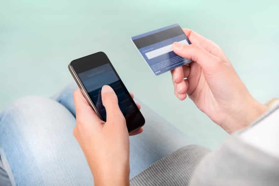 A hand holding a credit card and phone.