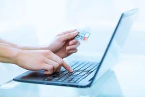 用笔记本电脑和信用卡在网上购物/支付的手特写。