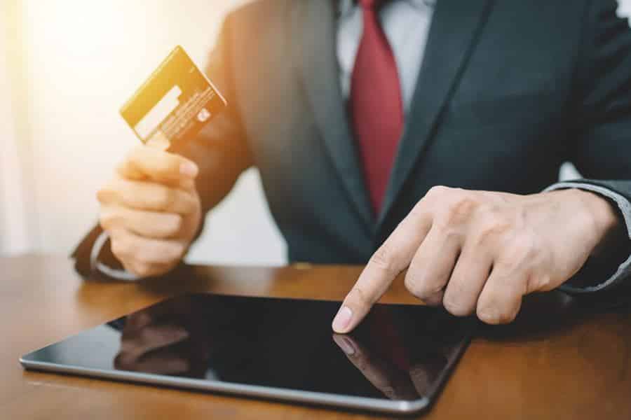 Businessman holding card ang checking tablet.