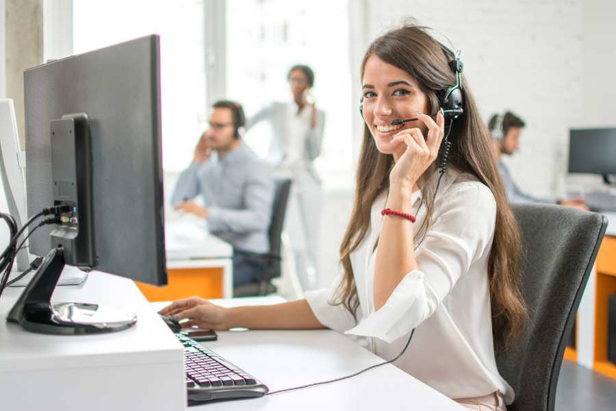 Woman operator wearing a headset with her teammates in the background.