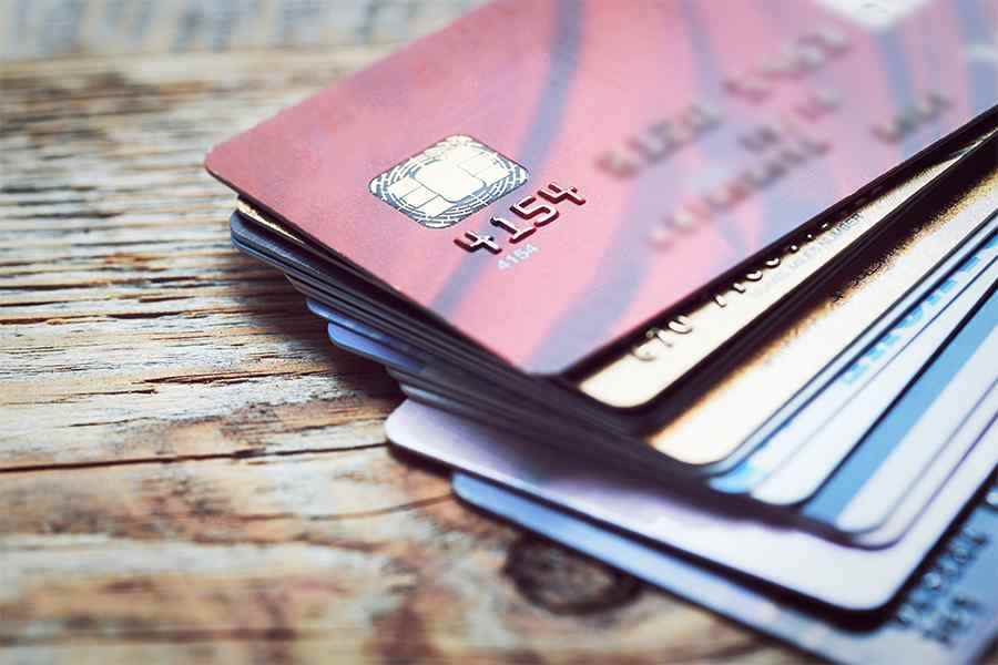 Pile of different credit cards on top of a wooden table.