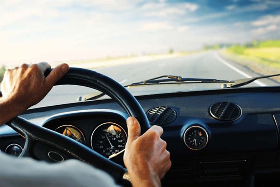 克罗se up shot of a man's hand gripping steering wheel while driving.
