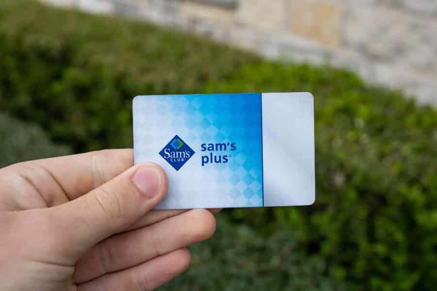 一只手持有Sam's Club Plus会员会员卡，该卡使用户可以访问Sam's Club Warehouse购物，奖励，廉价美食广场。