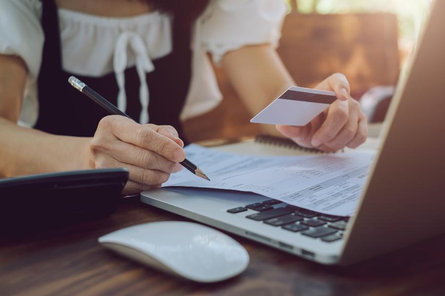 Woman holding a credit a card while checking bills.