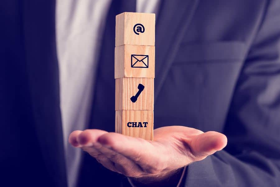 Businessman holding a stack of wooden cubes with communication icons on them.