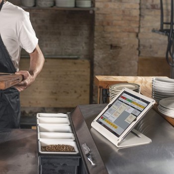 来uchBistro KDS screen tablet sitting on a restaurant kitchen countertop.