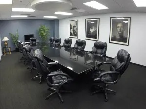 A conference room with black chairs and portraits of people hung on the white wall.
