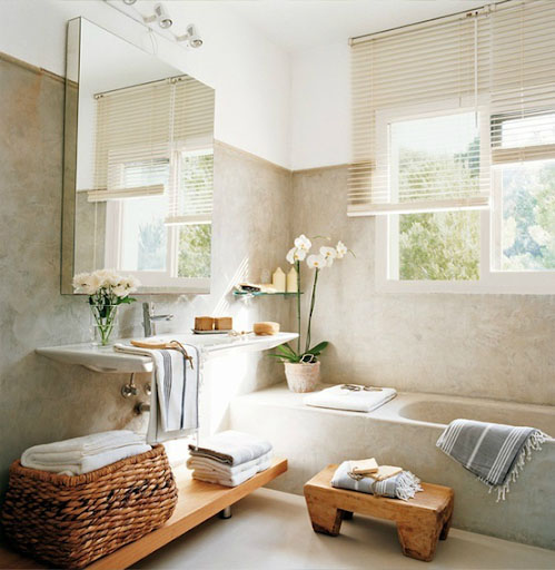 A staged bathroom with an orchid, a basket of white fluffy towels, and neutral tones.