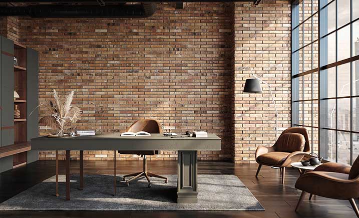 A home office with a brick wall, a large, gray table, brown seats, and floor-to-ceiling windows