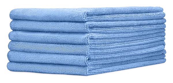 六件蓝色超细纤维衣服堆叠在白色背景上。